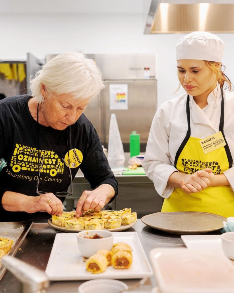 OzHarvest volunteer in Nourishing Our Country shirt plates frittata and sausage rolls beside a Nourish student chef
