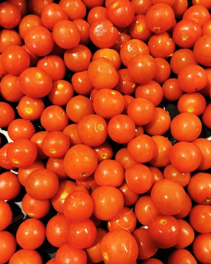 Mass of fresh red cherry tomatoes representing rescued surplus produce