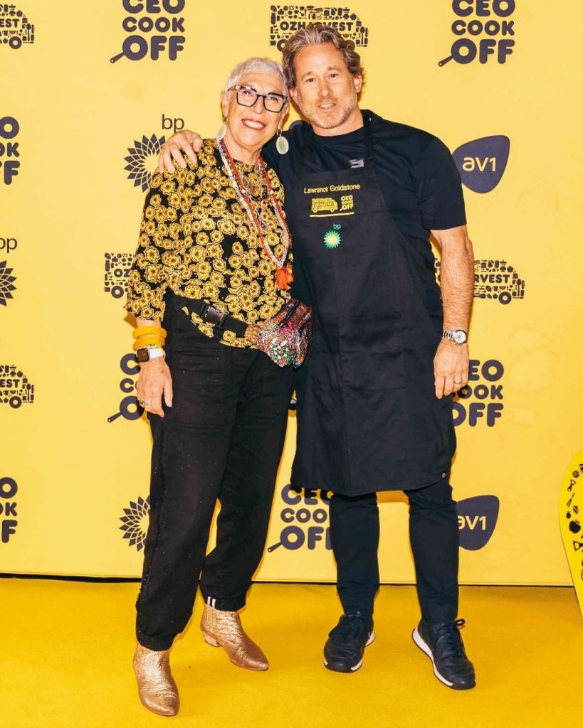 OzHarvest Chair Lawrence Goldstone poses with a guest on the yellow CEO Cook Off media wall